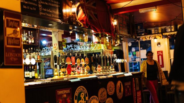 多様なビールタップとボトルが並ぶクラフトビールバーのカウンター