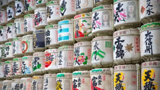 神社に奉納された色とりどりの菰樽(こもだる)が積み重なった壁。各蔵元の銘柄名が書かれたラベルが並んでいる