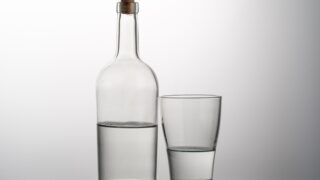 透明な瓶とグラスに注がれた透明な酒