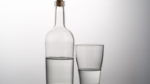 透明な瓶とグラスに注がれた透明な酒