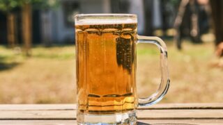 夏の屋外で冷えたビールグラスを持っている様子
