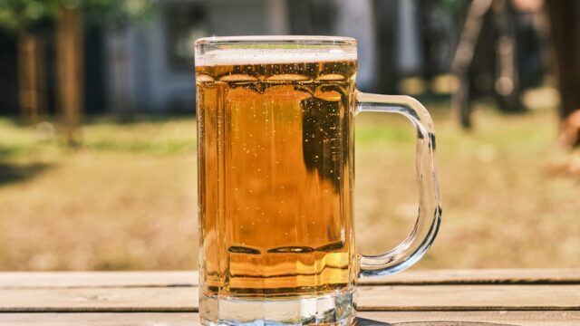 夏の屋外で冷えたビールグラスを持っている様子