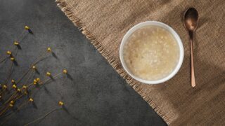 米粒の食感が残る白濁した甘酒風の飲み物が入った器と匙