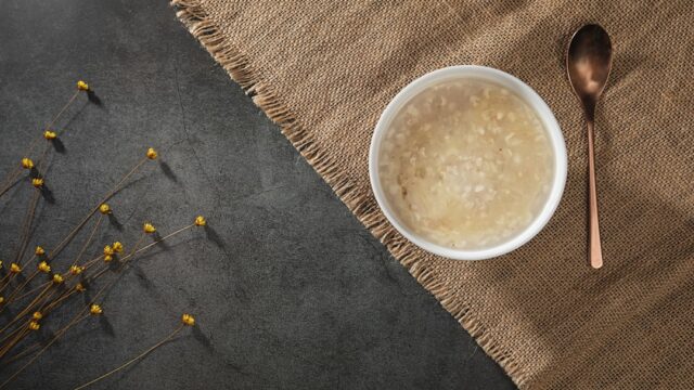 米粒の食感が残る白濁した甘酒風の飲み物が入った器と匙