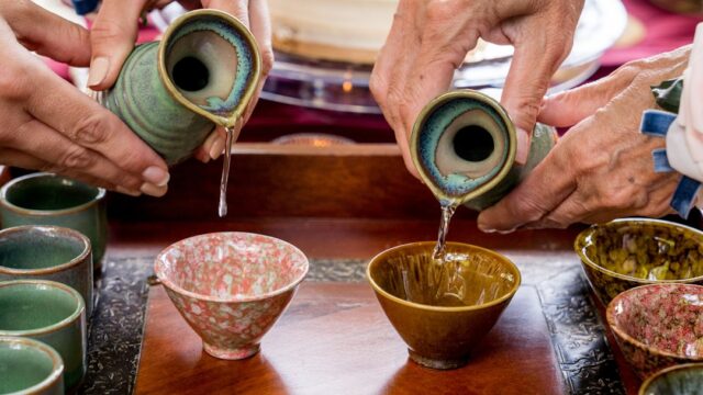 陶器の徳利からおちょこへ日本酒を注いでいる様子