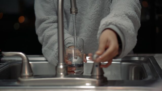 キッチンの蛇口でグラスに水を注いで洗っている様子