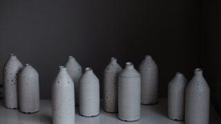 暗い背景に並ぶ白いセラミック製の酒瓶