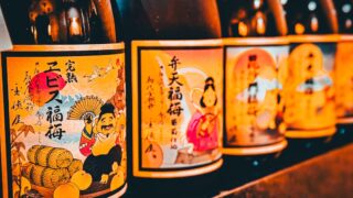 縁起物の絵柄が描かれたラベルの日本酒の瓶が複数並んでいる様子